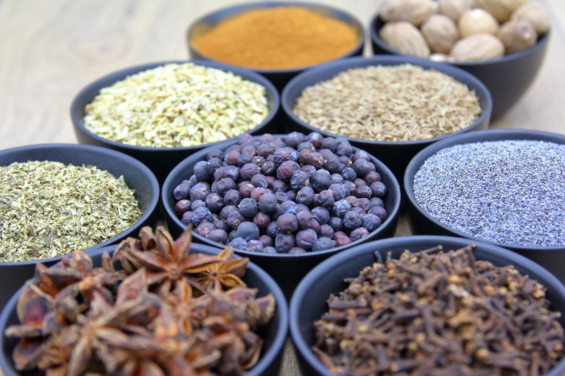 A flat lay of spices, dried chilies, garlic, fresh herbs and sauce bowls on dark wood
