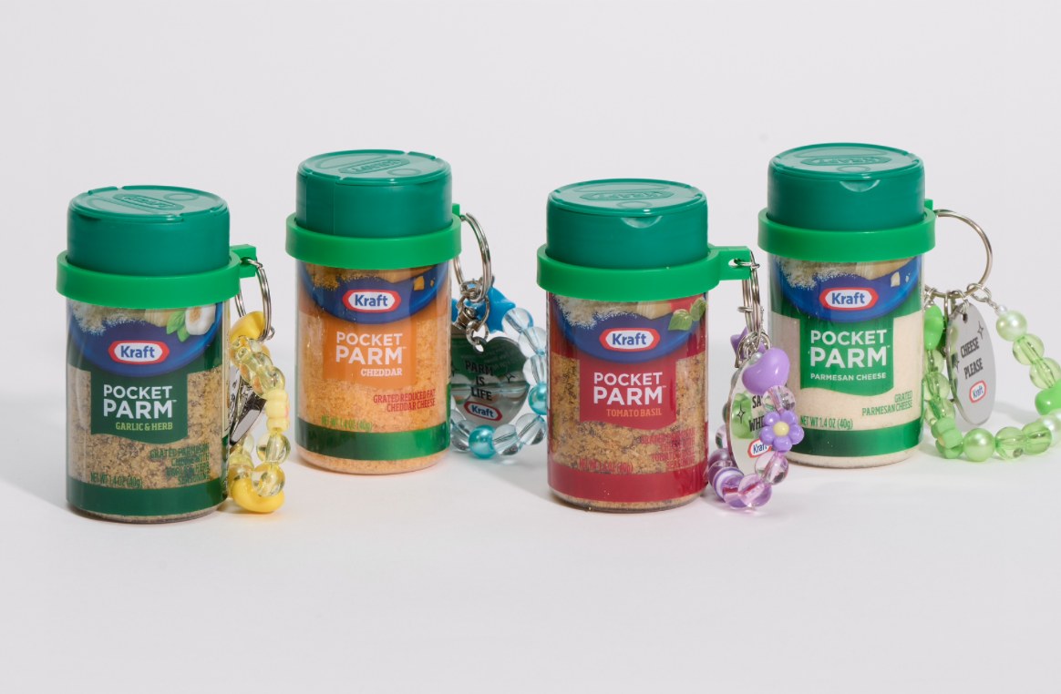 Four small green capped Kraft Pocket Parm bottles with beaded bag charms in Garlic and Herb, Cheddar, Tomato Basil, and Parmesan Cheese flavors lined up on a white background