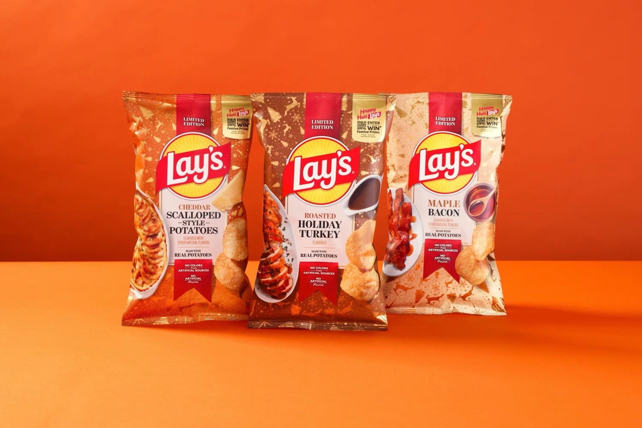 Three limited edition Lay's holiday chip bags on an orange background: Cheddar Scalloped Style Potatoes, Roasted Holiday Turkey, and Maple Bacon