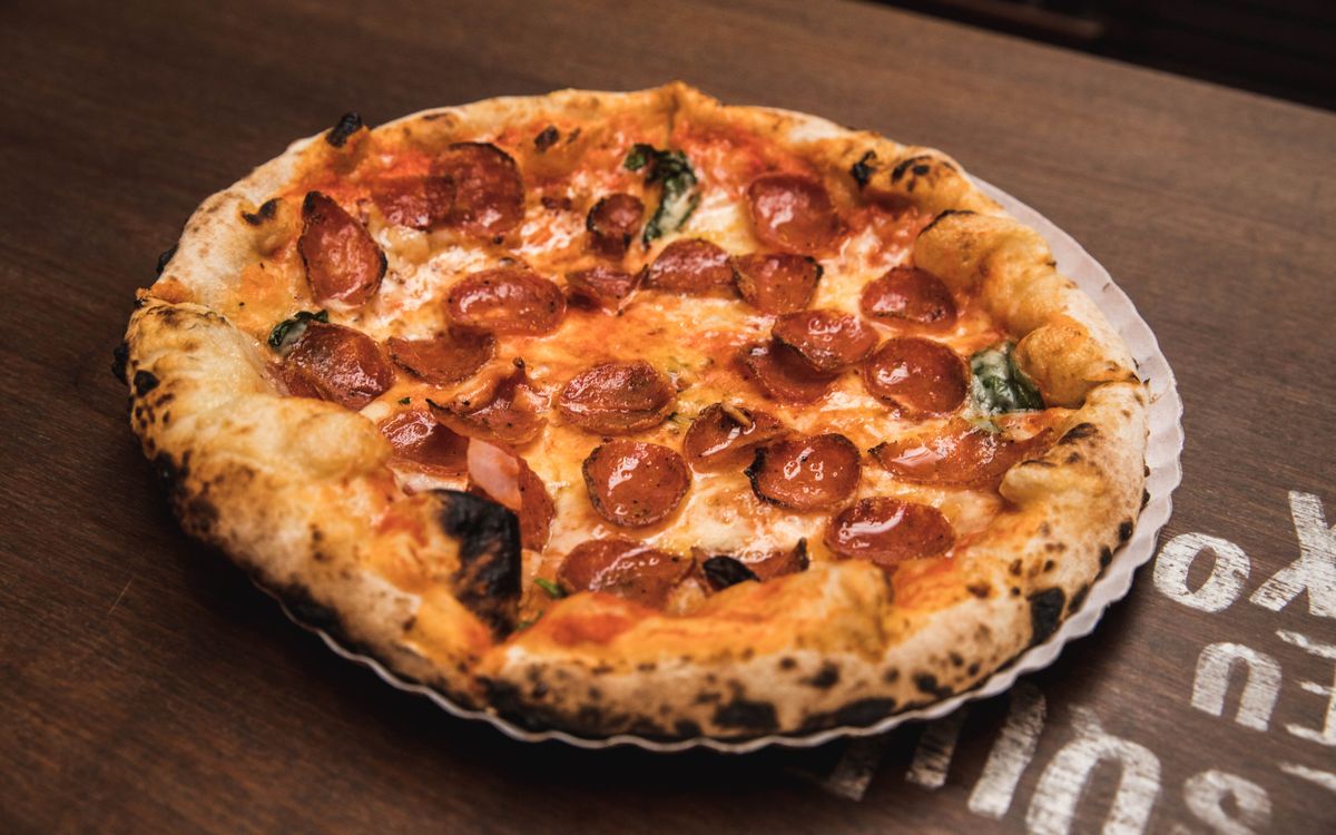 A pepperoni pizza fresh out of a wood-fired oven