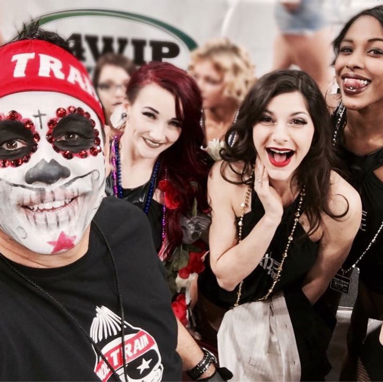 Moe Train in Wing Bowl face paint and his MOE TRAIN headband, taking a selfie with the Wingettes at the 94WIP backdrop