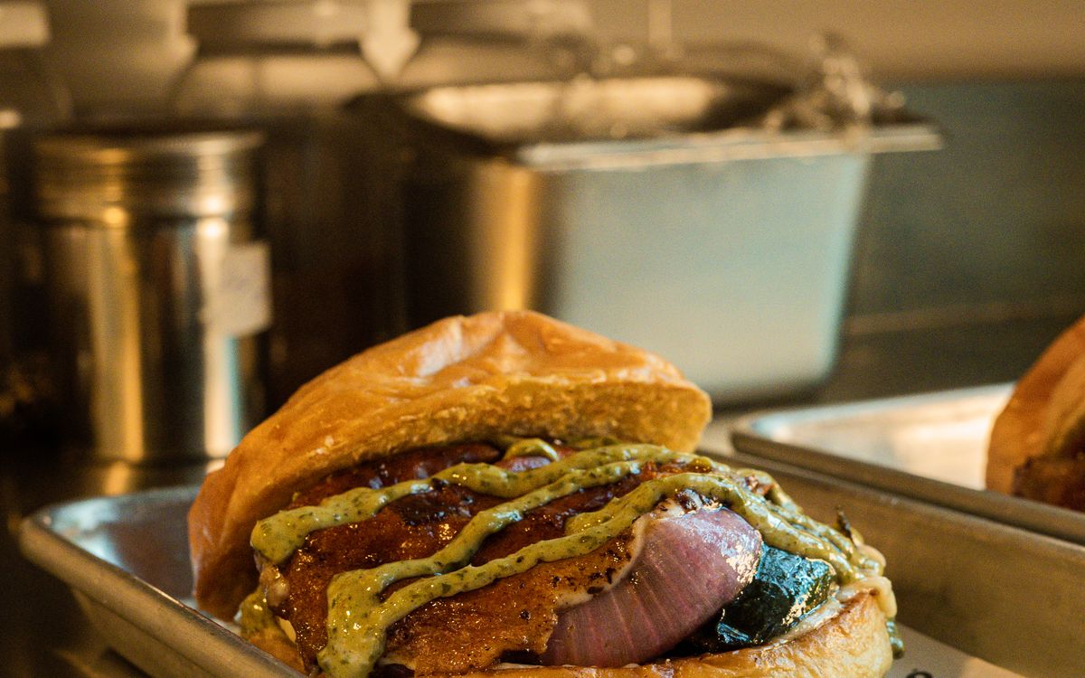 A stacked burger with melted cheese on a kitchen tray
