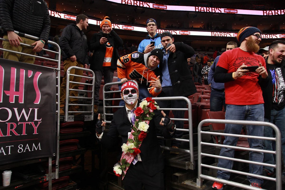 Moe Train in the stands at Wing Bowl 25, suit and rose garland on, red MOE TRAIN headband, fans all around him