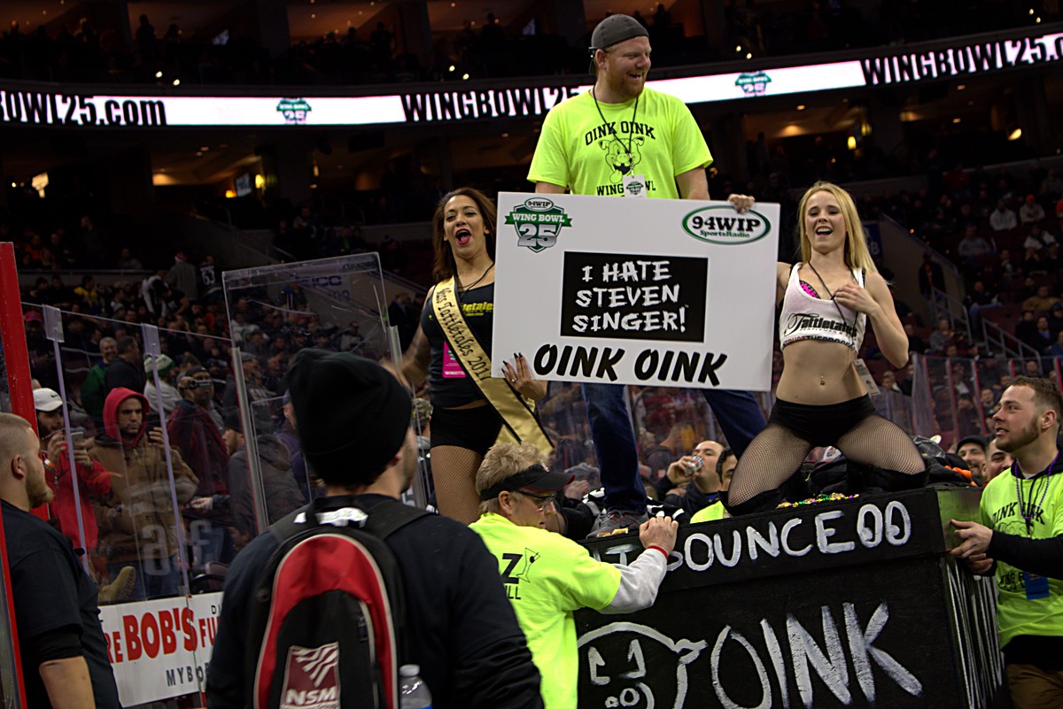An entrance float with a large sign moving through the arena under lit ring boards at Wing Bowl 25