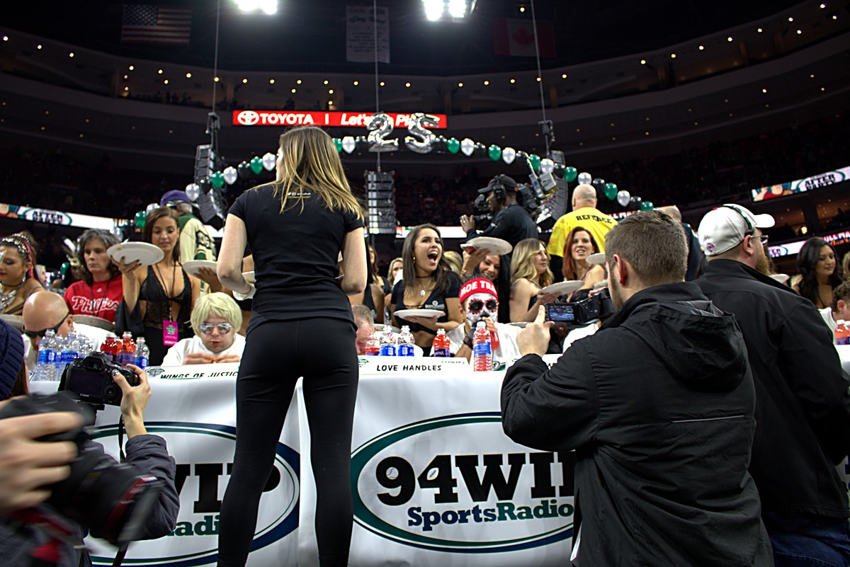 Behind the competition table with photographers and arena lights at Wing Bowl 25