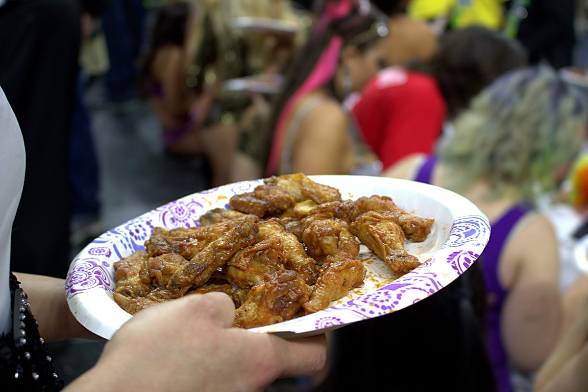 Close-up of a paper plate piled with chicken wings being carried through the crowd at Wing Bowl 25